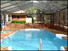 Bronze Gable-Hip Style Pool Enclosure that terraces down a brick pony-wall
